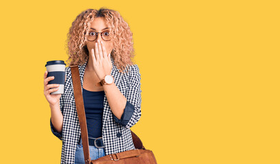 Young blonde woman with curly hair wearing leather bag and drinking a take away cup of coffee covering mouth with hand, shocked and afraid for mistake. surprised expression