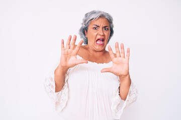 Senior hispanic grey- haired woman wearing casual clothes afraid and terrified with fear expression stop gesture with hands, shouting in shock. panic concept.