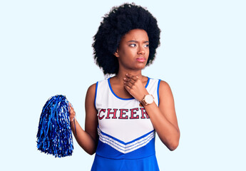Young african american woman wearing cheerleader uniform holding pompom touching painful neck, sore...