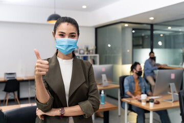Asian young businesswoman wearing mask working on computer in office