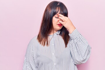 Young plus size woman wearing casual clothes tired rubbing nose and eyes feeling fatigue and headache. stress and frustration concept.