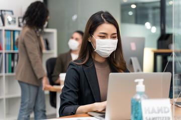 Asian young businesswoman wearing mask working on computer in office.