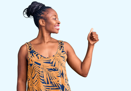 Young african american woman wearing casual clothes looking proud, smiling doing thumbs up gesture to the side