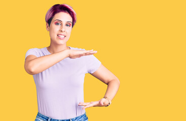 Young beautiful woman with pink hair wearing casual clothes gesturing with hands showing big and large size sign, measure symbol. smiling looking at the camera. measuring concept.