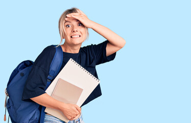 Young beautiful blonde woman wearing student backpack holding notebook stressed and frustrated with hand on head, surprised and angry face