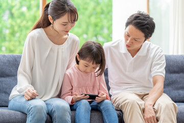 ソファーに座ってスマートフォンを使う親子