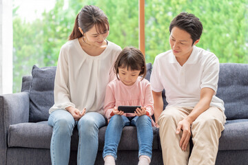 ソファーに座ってスマートフォンを使う親子