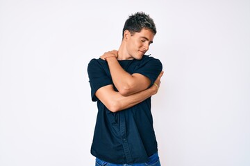 Fototapeta premium Young handsome man wearing casual clothes hugging oneself happy and positive, smiling confident. self love and self care