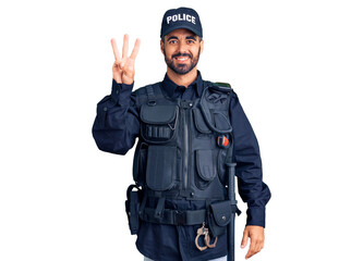 Young hispanic man wearing police uniform showing and pointing up with fingers number three while smiling confident and happy.