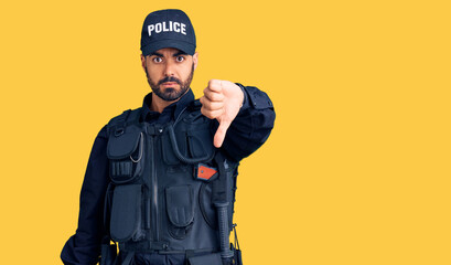 Young hispanic man wearing police uniform looking unhappy and angry showing rejection and negative with thumbs down gesture. bad expression.