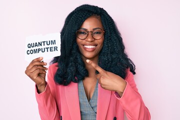 Beautiful african woman holding quantum computer banner smiling happy pointing with hand and finger