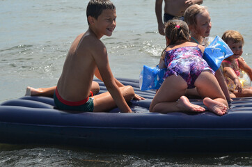 Obraz premium Caucasian children outdoor in summer swimming with inflatable mattress