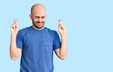 Naklejka premium Young handsome man wearing casual t shirt gesturing finger crossed smiling with hope and eyes closed. luck and superstitious concept.