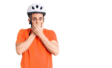 Young handsome man wearing bike helmet shocked covering mouth with hands for mistake. secret concept.