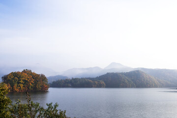 Obraz premium Beautiful autumn scenery,foggy mist over the lake and mountain.