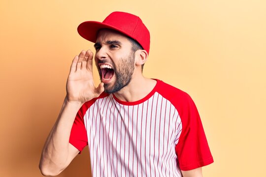 Young handsome man with beard wearing baseball cap and t-shirt shouting and screaming loud to side with hand on mouth. communication concept.