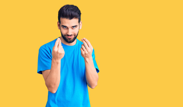 Young handsome man with beard wearing casual t-shirt doing money gesture with hands, asking for salary payment, millionaire business