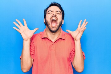 Naklejka premium Young hispanic man wearing casual clothes celebrating mad and crazy for success with arms raised and closed eyes screaming excited. winner concept