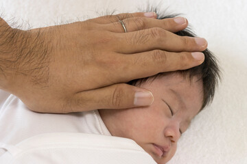 Fototapeta na wymiar 生後1カ月の赤ちゃんの頭を撫でる男性の手