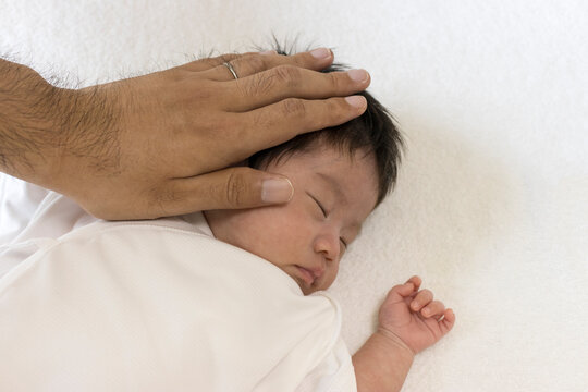 生後1カ月の赤ちゃんの頭を撫でる男性の手