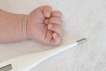 生後一ヶ月の赤ちゃんの手とデジタル体温計
