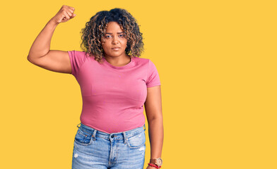 Young african american plus size woman wearing casual clothes strong person showing arm muscle, confident and proud of power