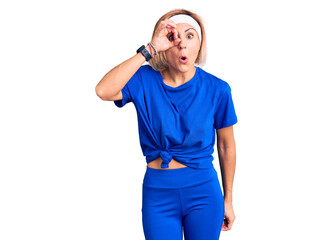 Fototapeta premium Young blonde woman wearing sportswear doing ok gesture shocked with surprised face, eye looking through fingers. unbelieving expression.