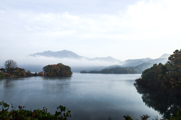 Fototapeta na wymiar Beautiful autumn scenery, water mist over the lake and sea clouds on the mountain at dawn.