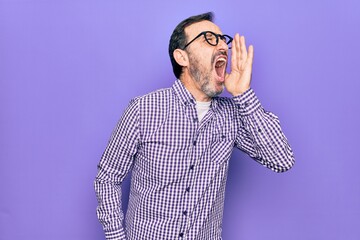 Middle age handsome man wearing casual shirt and glasses over isolated white background shouting and screaming loud to side with hand on mouth. Communication concept.