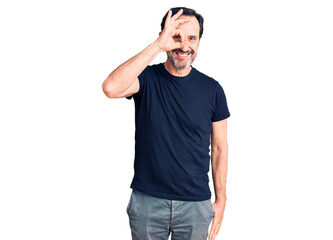 Fototapeta premium Middle age handsome man wearing casual t-shirt doing ok gesture with hand smiling, eye looking through fingers with happy face.