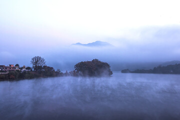 Beautiful autumn scenery, water mist over the lake and sea clouds on the mountain at dawn.