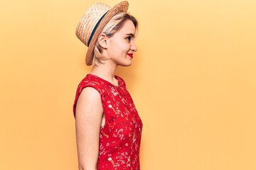 Young beautiful blonde woman wearing summer hat looking to side, relax profile pose with natural face with confident smile.