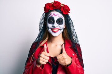 Woman wearing day of the dead costume with thumbs up doing ok sign smiling with a happy and cool smile on face. showing teeth.