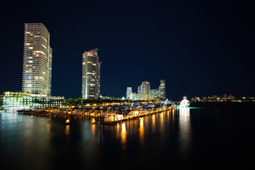 Miami city skyline panorama at dusk with urban skyscrapers and bridge over sea with reflection. Night in Miami.