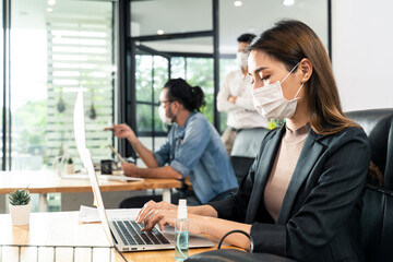 Asian young businesswoman wearing mask working on computer in office