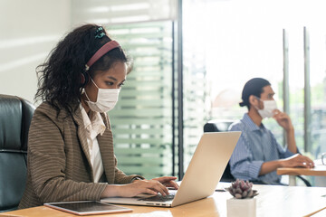 Asian young businesswoman wearing mask working on computer in office