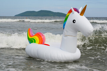 Inflatable toy circle unicorn floats in the sea on the waves in summer. Concept of child safety and active summer games