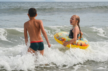 Caucasian children outdoor on the beach in summer lifestyle swim in the sea