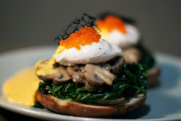 Poached egg with spinach, mushrooms topping with red caviar on burger. Wooden cutting board isolated on Dark Slate Gray Concrete Wall background