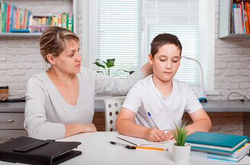 Fototapeta premium The tutor is engaged with the child, teaches to write and count
