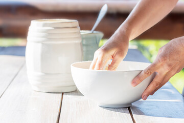 The woman holds the bowl in which she is kneading the dough