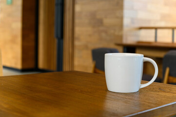 white coffee cup with hot cappuccino coffee on wooden table in coffee cafe. copy space for adding text