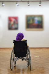 Disabled girl with purple hair in a wheelchair at the art gallery