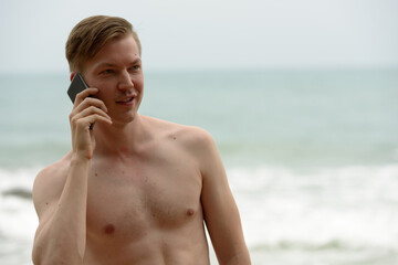 Young handsome shirtless tourist man relaxing at the beach