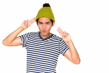 Studio shot of Asian man making peace sign isolated against white background