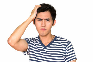 Studio shot of young serious Asian man isolated against white background
