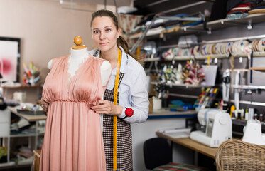 Woman is thinking about modern design near mannequin for new fashion collection in the workshop.