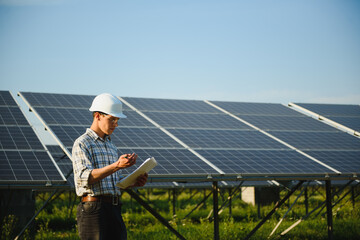 The portrait of a young engineer checks photovoltaic solar panels. Concept: renewable energy,...