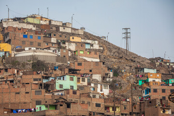 Fototapeta na wymiar Houses and apartments are built into the hillside and on top of each other in a poor neighborhood in Lima, Peru.