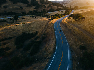 Solo Bike rider on a country road during sunset, Drone aerial